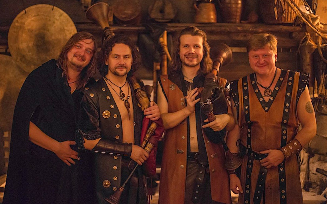 Musicians in medieval attire holding bagpipes at a themed dinner event.