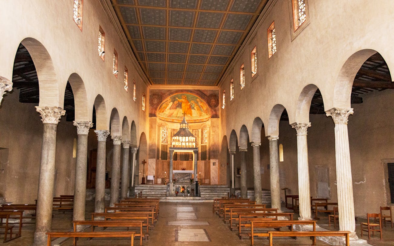 Interior of the Basilica of San Giorgio in Velabro, Rome, with ancient columns and frescoed apse.