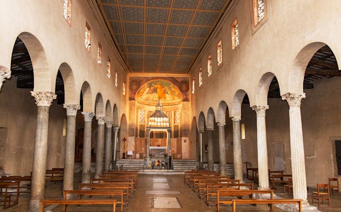 Interior of the Basilica of San Giorgio in Velabro, Rome, with ancient columns and frescoed apse.