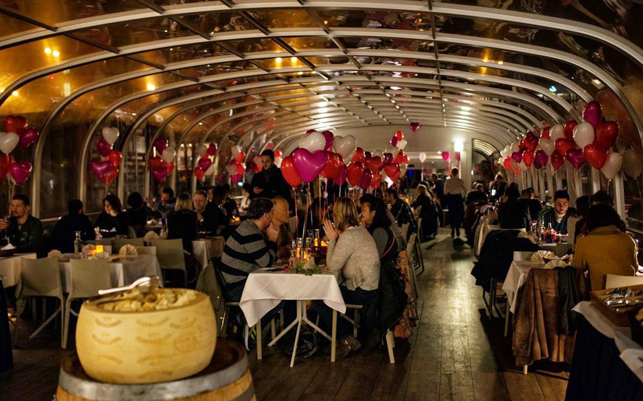 Couples dining on a Valentine’s Day candle-lit dinner cruise with heart-shaped balloons and live music.