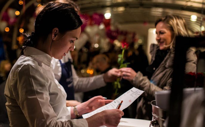 Server taking reservation for Valentine’s Day candle-lit dinner cruise with live music.