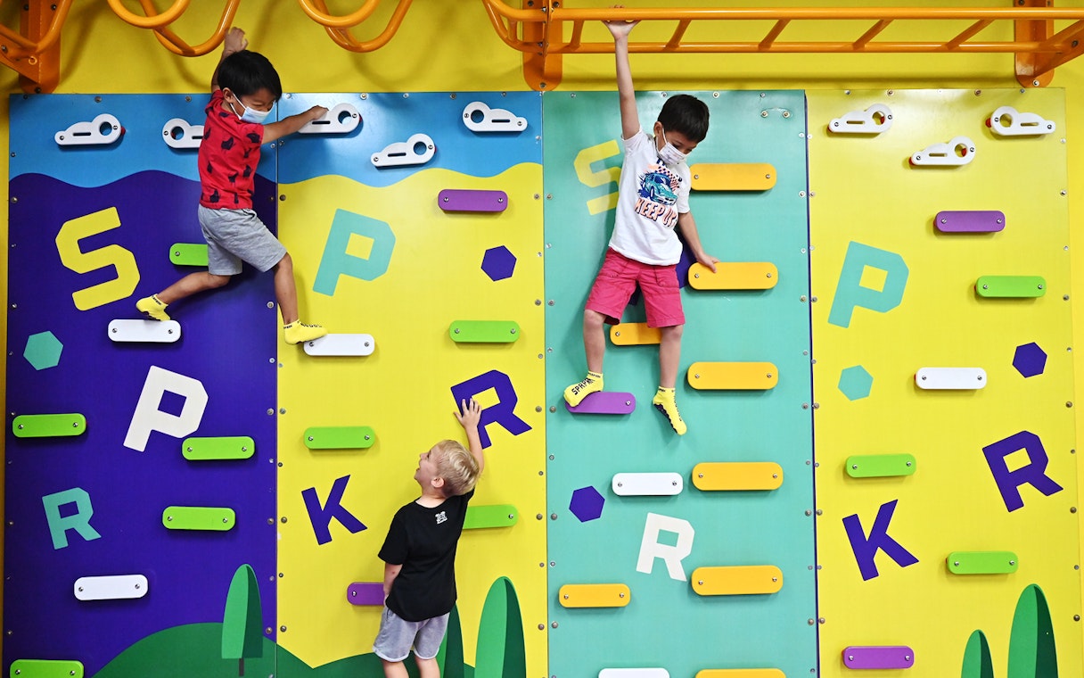 Children climbing colorful wall at SuperPark Singapore.