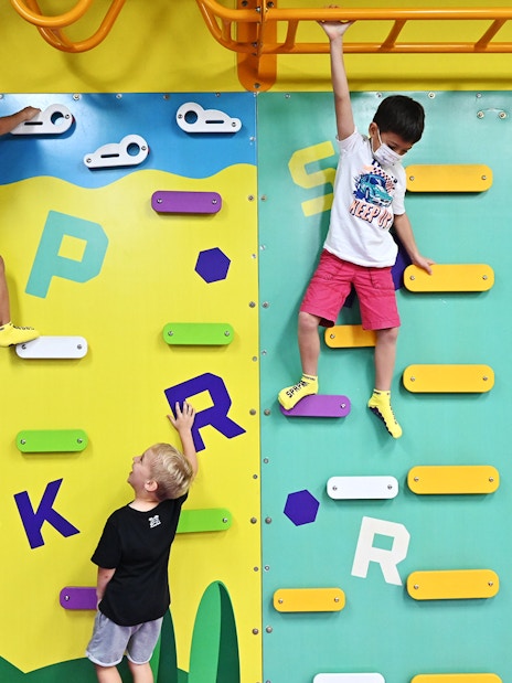 Children climbing colorful wall at SuperPark Singapore.
