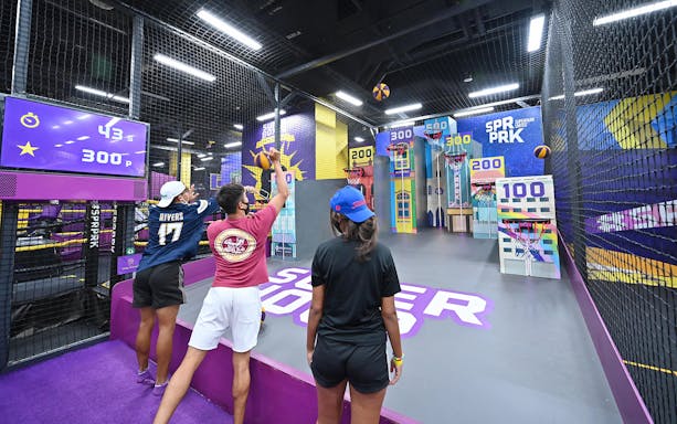 Visitors playing basketball game at SuperPark Singapore indoor activity center.