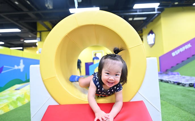 Child playing in a yellow tunnel at SuperPark Singapore indoor playground.