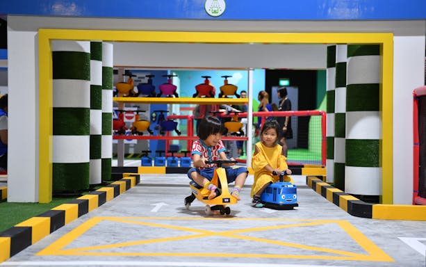Children riding toy vehicles at Tayo Station indoor playground.