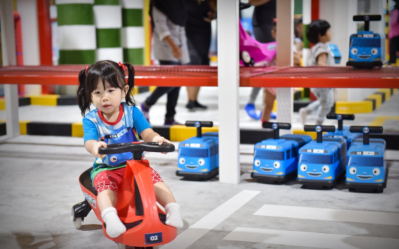 Child riding toy vehicle at Tayo Station indoor playground.