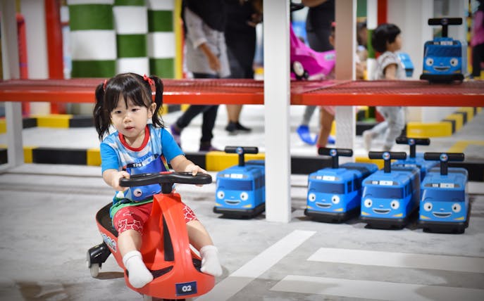 Child riding toy vehicle at Tayo Station indoor playground.
