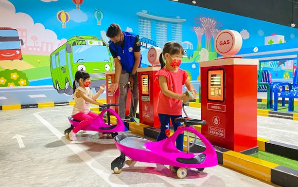 Children playing at Tayo Station gas pump area with colorful cartoon backdrop.