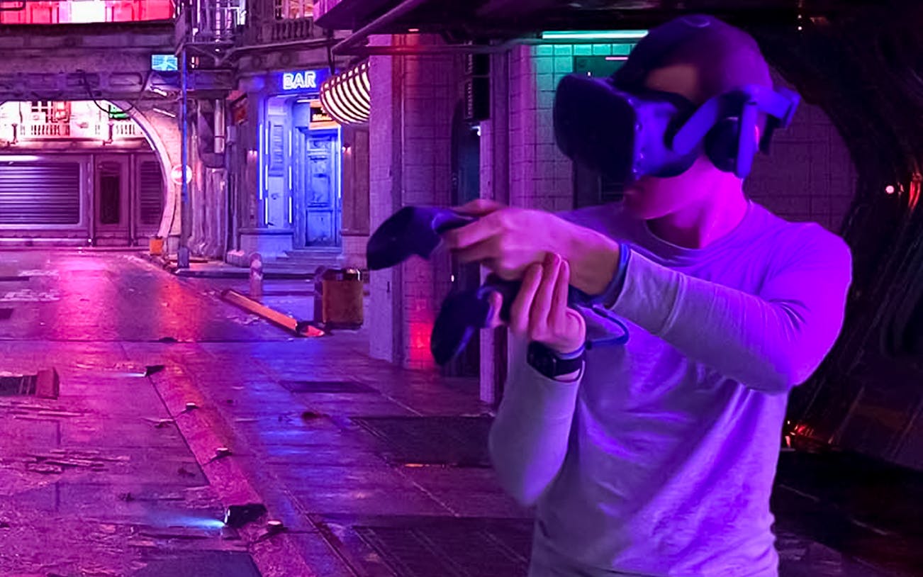 Person using VR headset in neon-lit Apsis VR Escape Room.