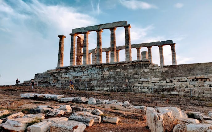 Temple of Poseidon at Cape Sounion with visitors exploring the ancient ruins.