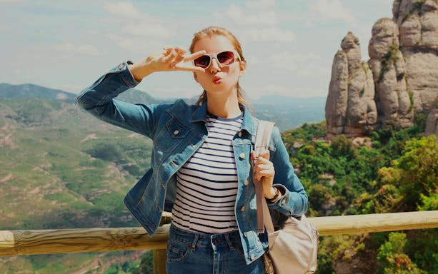Visitor posing at Montserrat Monastery viewpoint, Barcelona, with rocky landscape in background.