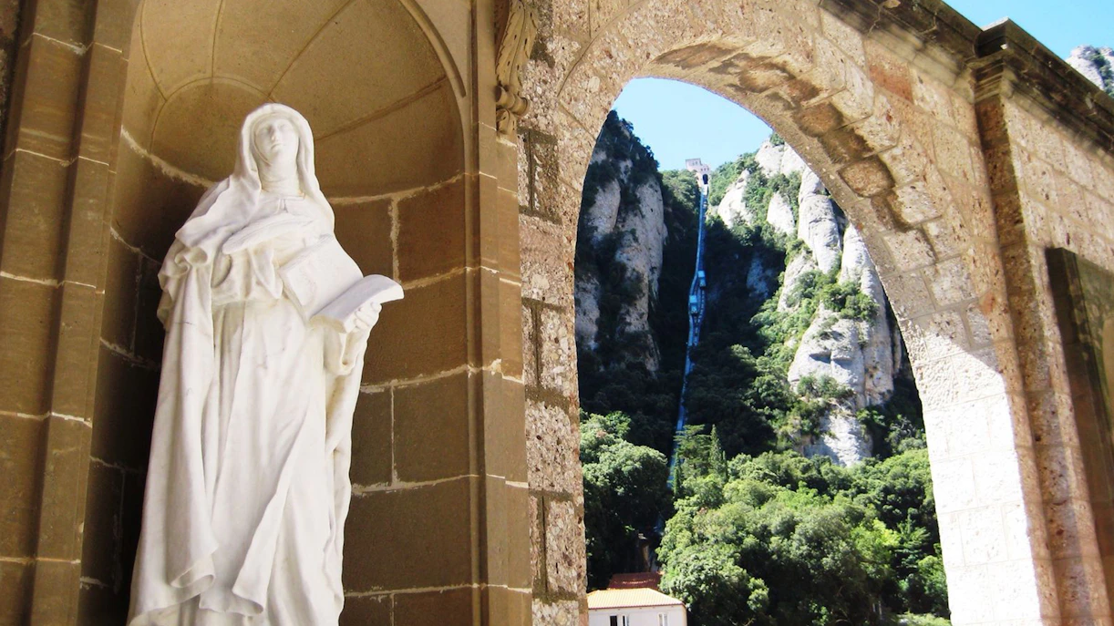 Statue at Montserrat Monastery with mountain backdrop, Barcelona tour.