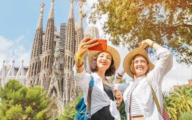 Tourists taking a selfie in front of Sagrada Familia in Barcelona.