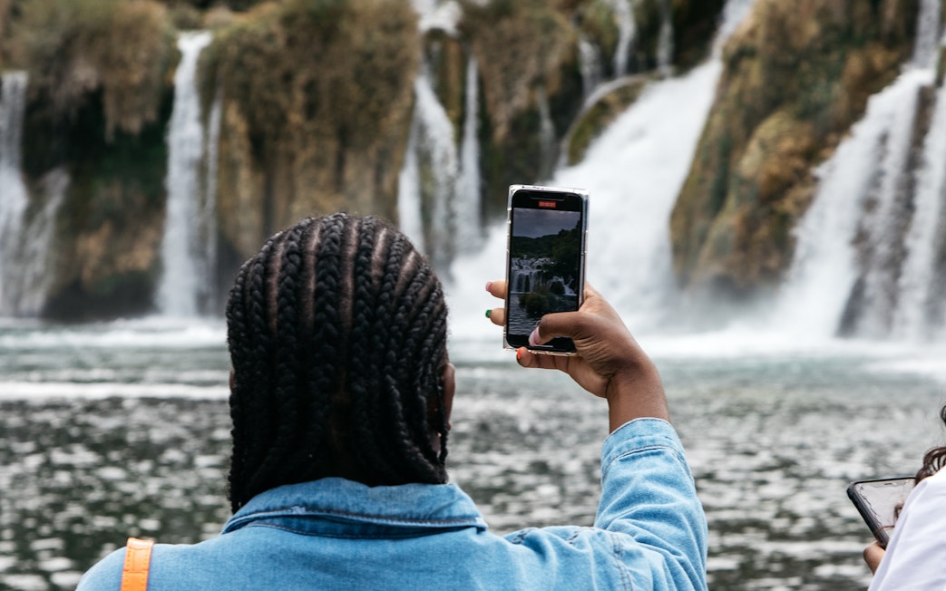 Visitor photographing waterfalls at Krka National Park during tour from Split.
