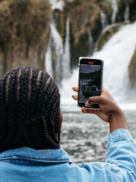 Visitor photographing waterfalls at Krka National Park during tour from Split.