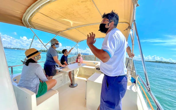 Yacht guide leading a Southern Islands tour with passengers seated under a canopy.