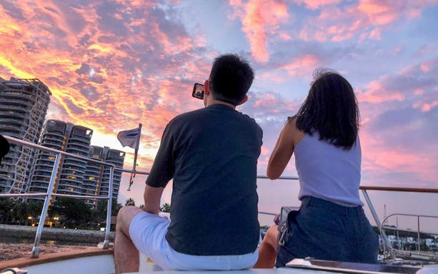 Couple enjoying sunset on Southern Islands yacht tour with city skyline.