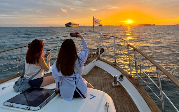 Yacht tour at sunset with two people taking photos, Southern Islands, 2.5-hour guided experience.