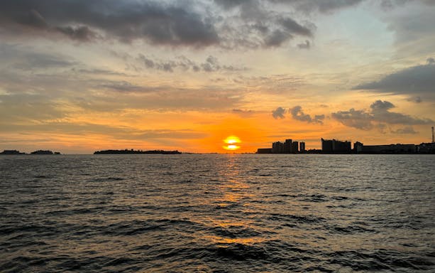 Sunset over city skyline viewed from a cruise on the water.