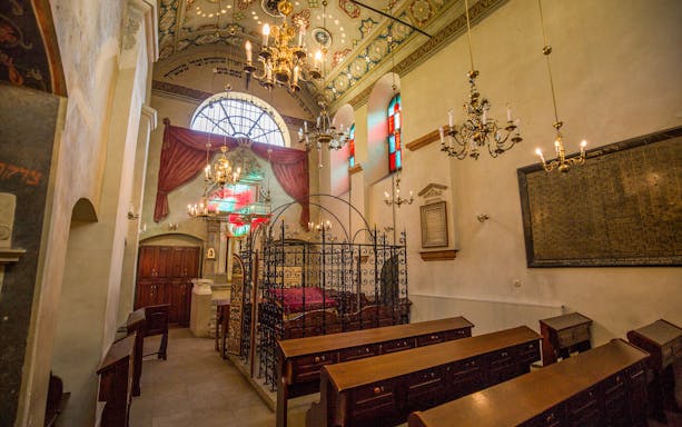 Interior of Old Synagogue in Kazimierz, Krakow, featuring ornate chandeliers and stained glass windows.