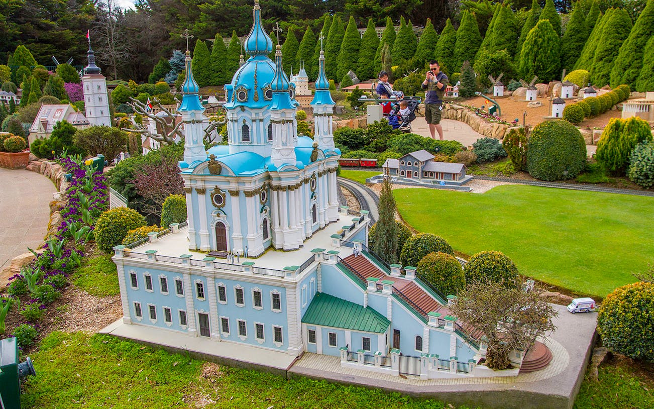 Miniature blue-domed building at Cockington Green Gardens with visitors exploring.