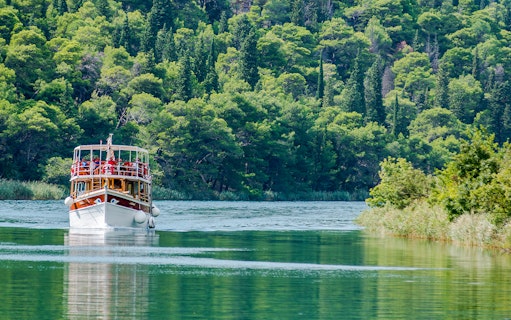 Boat on Krka River surrounded by lush greenery during Split tour.
