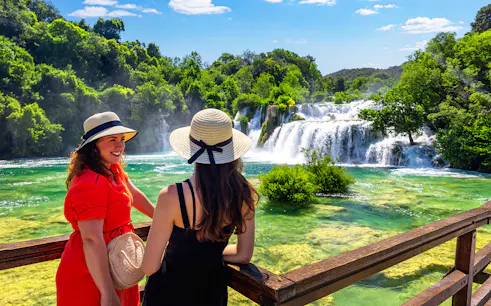 Visitors enjoying the view of Krka waterfalls from a wooden deck, Split tour.