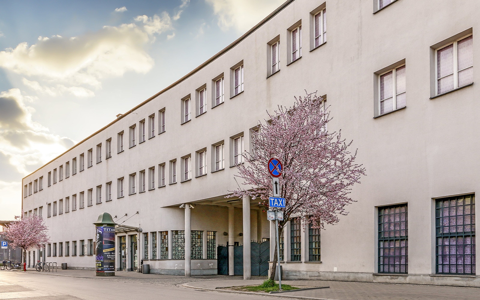 Schindler's Factory exterior in Krakow with blooming trees nearby.