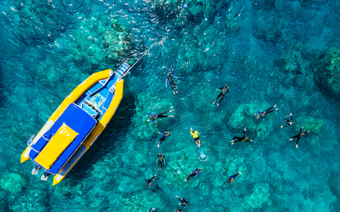 Snorkelers near a yellow raft in clear Whitsundays waters, Australia.