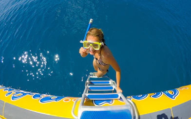 Snorkeler climbing onto raft in Whitsundays Fly + Raft Package tour.