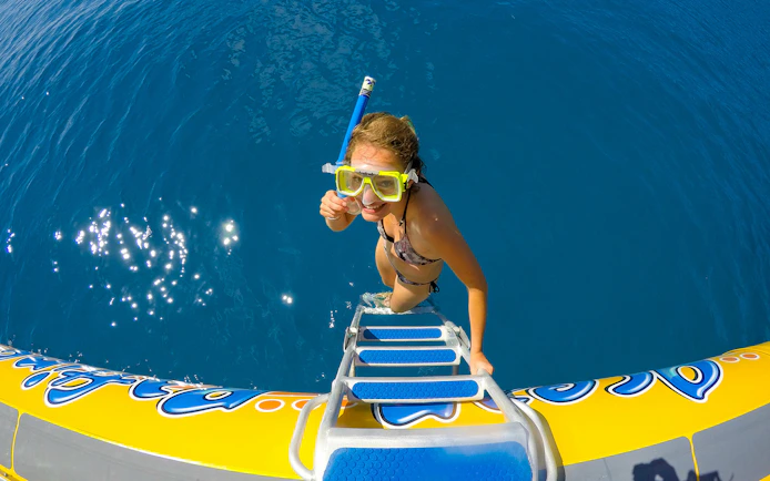 Snorkeler climbing onto raft in Whitsundays Fly + Raft Package tour.