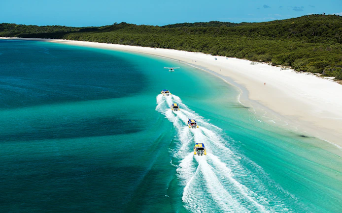 Rafting boats and seaplane over turquoise waters near Whitsundays beach.