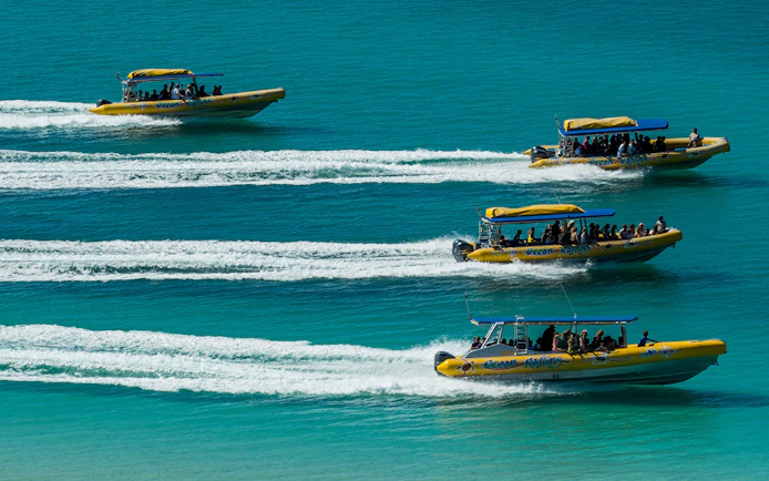 Speedboats with tourists on Whitsundays Fly + Raft Package tour in turquoise waters.