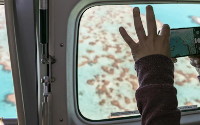 Aerial view of Whitsundays coral reefs through plane window during scenic flight.