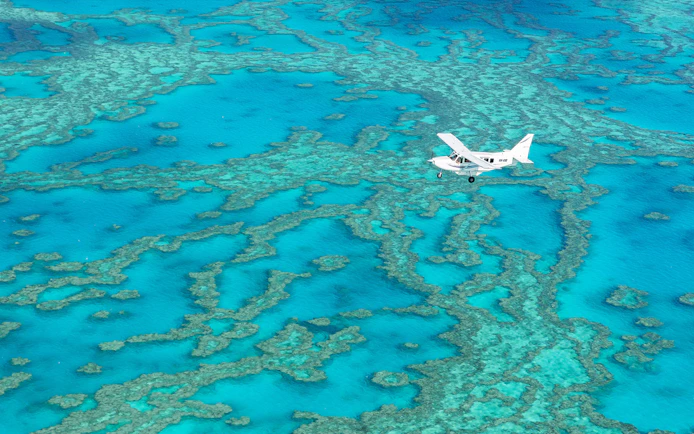 Aerial view of a plane flying over the Great Barrier Reef during Whitsundays scenic flight.
