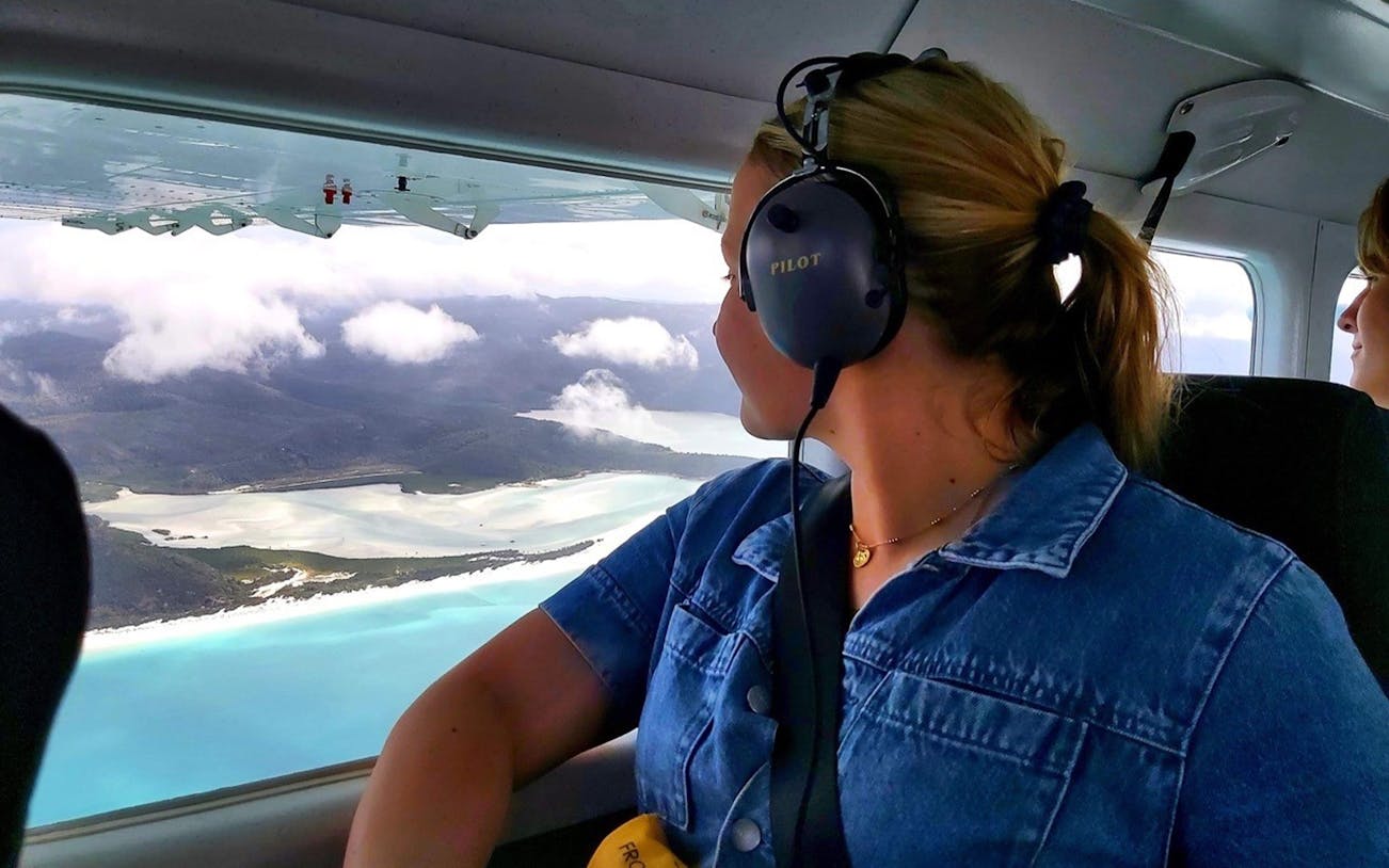Person viewing Whitsundays from plane during scenic flight.