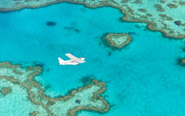 Aerial view of a plane over the Great Barrier Reef during Whitsundays scenic flight.