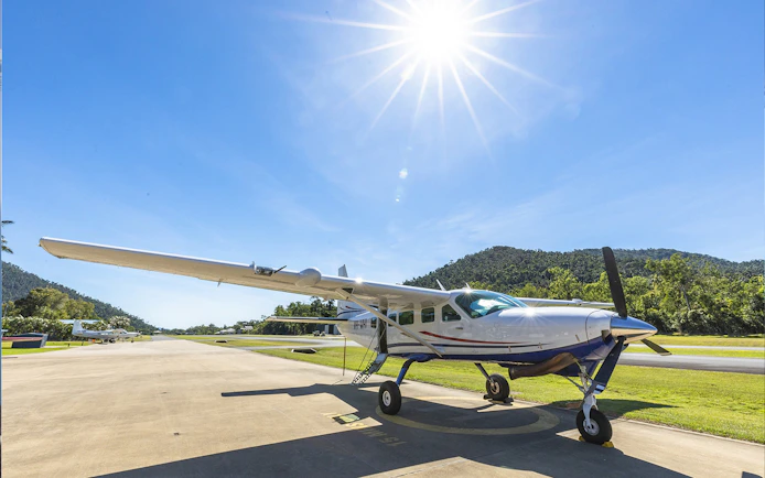 Small plane on runway under clear sky for Whitsundays scenic flight.