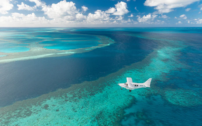 Aerial view of a plane flying over the turquoise waters of the Whitsundays during a scenic flight.