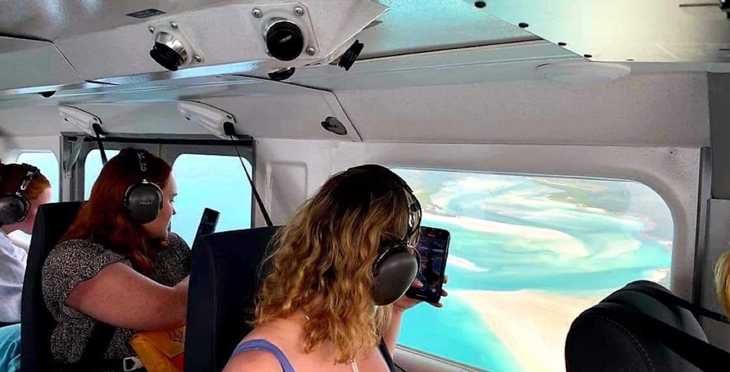 Passengers view Whitsundays from plane window during scenic flight.