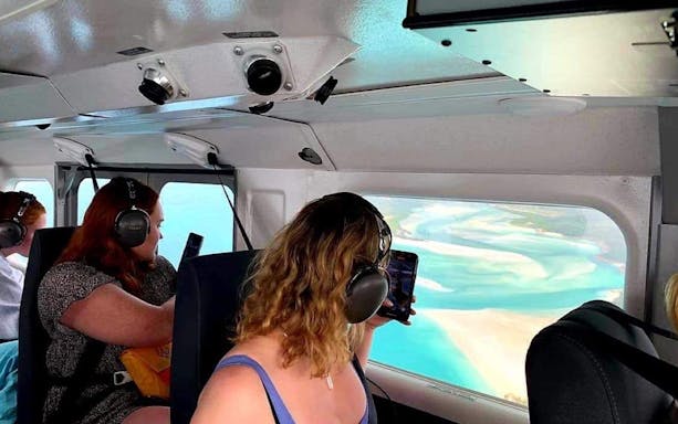 Passengers view Whitsundays from plane window during scenic flight.