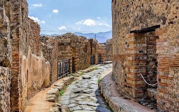 Ancient stone street in Pompeii with ruins, viewed on a tour from Rome by high-speed train.