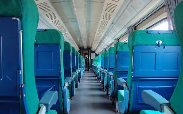 Interior of high-speed train from Rome to Pompeii, showing rows of blue and green seats.