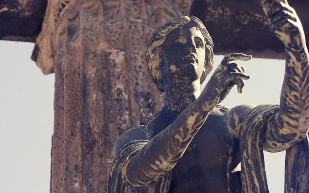 Ancient statue in Pompeii with detailed carvings, viewed on a tour from Rome by high-speed train.