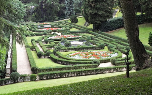 Vatican Gardens with manicured hedges and colorful flower beds, Rome, Italy.