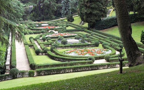 Vatican Gardens with manicured hedges and colorful flower beds, Rome, Italy.