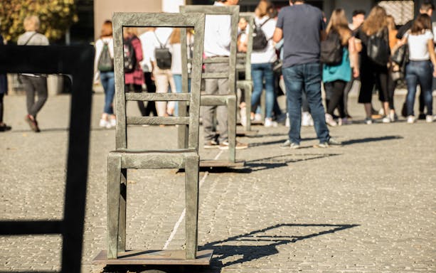 Chairs in Ghetto Heroes Square, Krakow, with tourists in the background.