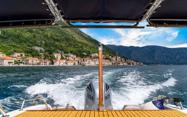 Speedboat view approaching Kotor Bay with coastal town and mountains in Montenegro.