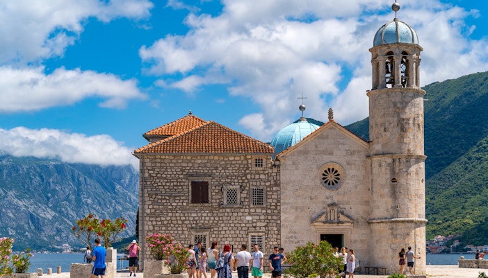 Tourists enjoying a speedboat tour of Kotor Bay with a view of Our Lady of the Rocks island in the background